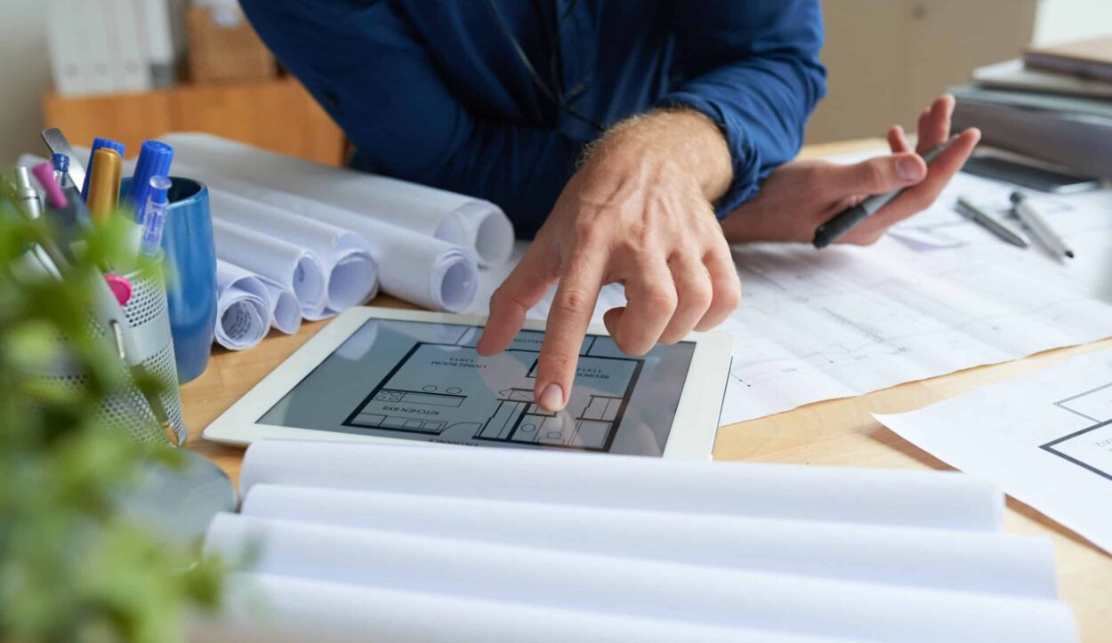 Close-up image of architect examining housing project on screen of tablet computer