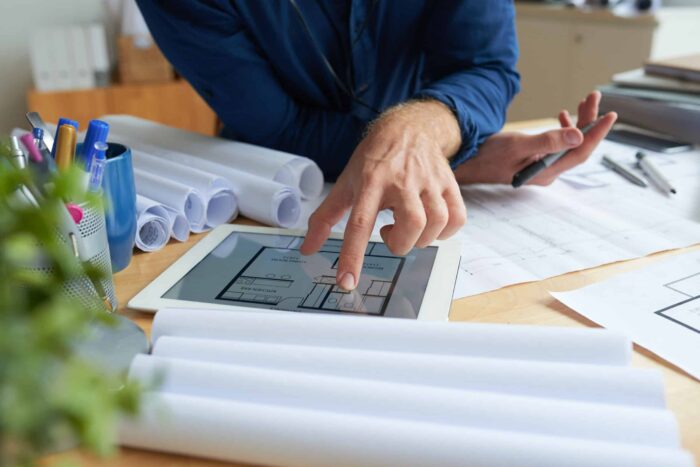 Close-up image of architect examining housing project on screen of tablet computer